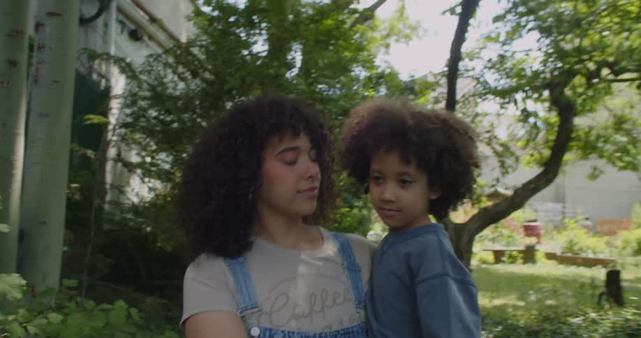 A young woman carrying a child as they explore a garden