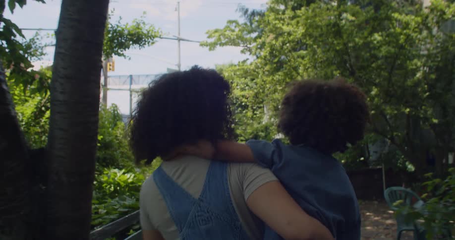 A young woman carrying a child through a garden