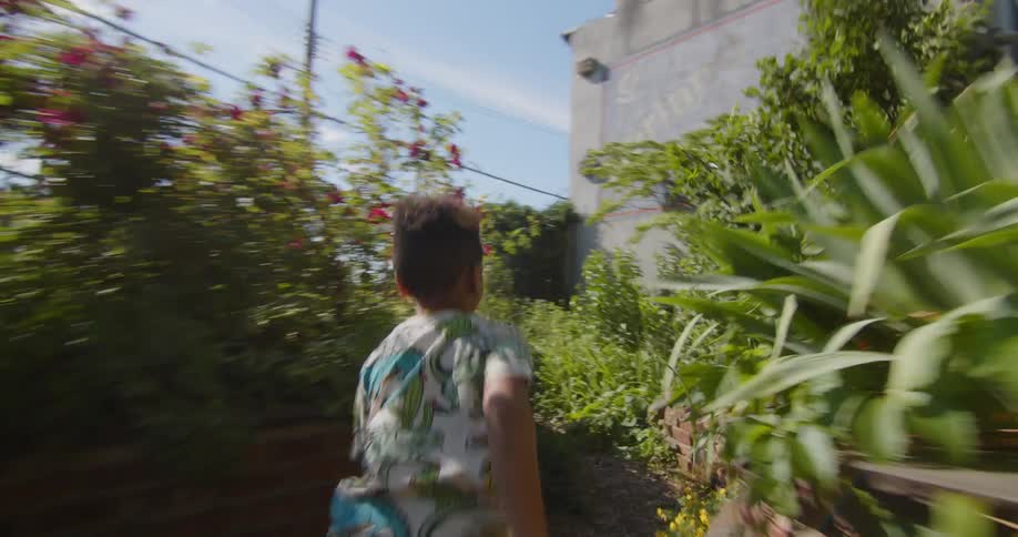 A black boy runs along a path through a city garden