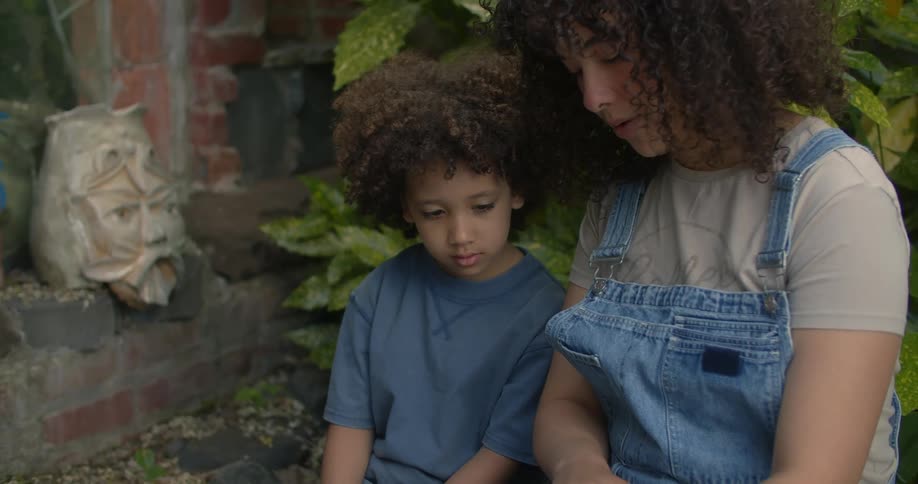 A mother is reading to her son in an outdoor garden nook
