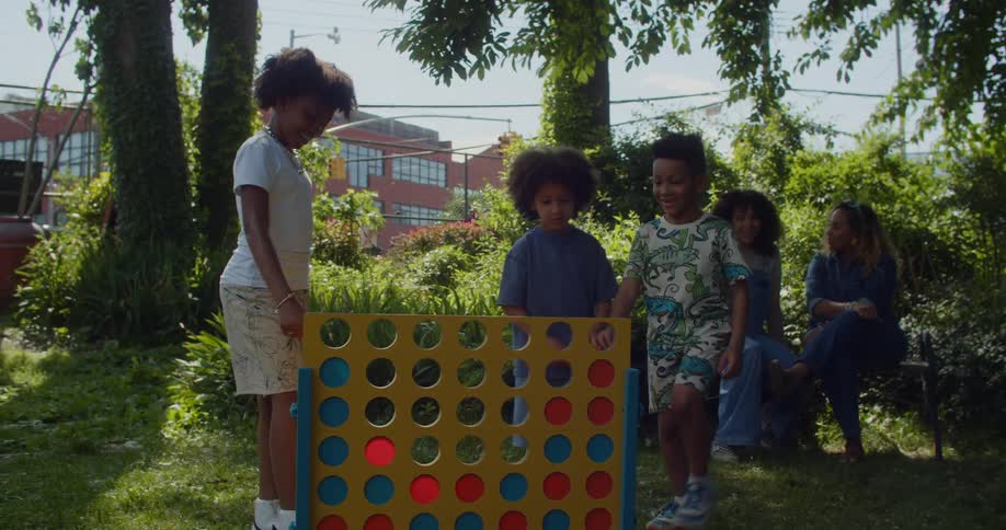 A group of children playing a large game of connect four in a city garden