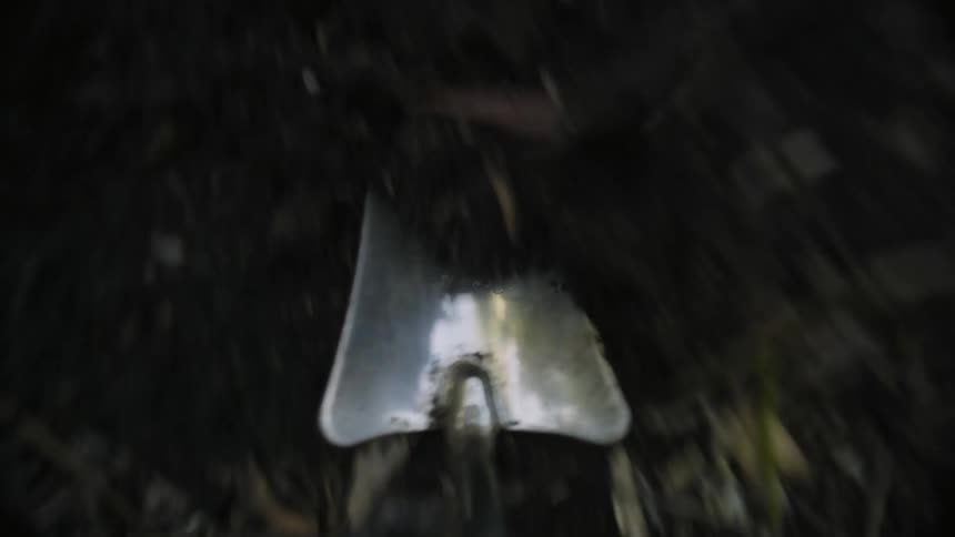 A small metal trowel digging into and lifting a mound of dirt