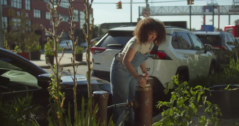 Woman on the street sidewalk opening a water gasket with a wrench