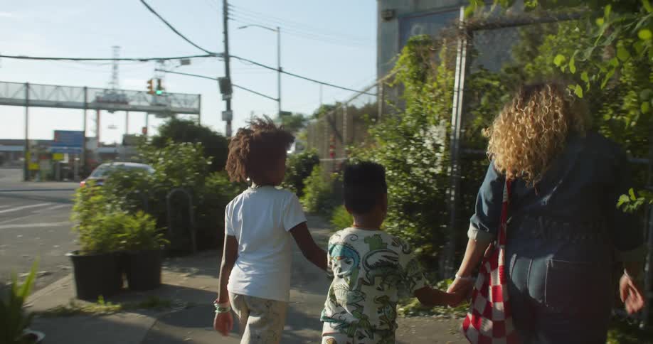 A mom out for a walk with her kids as they meet friends at the community garden