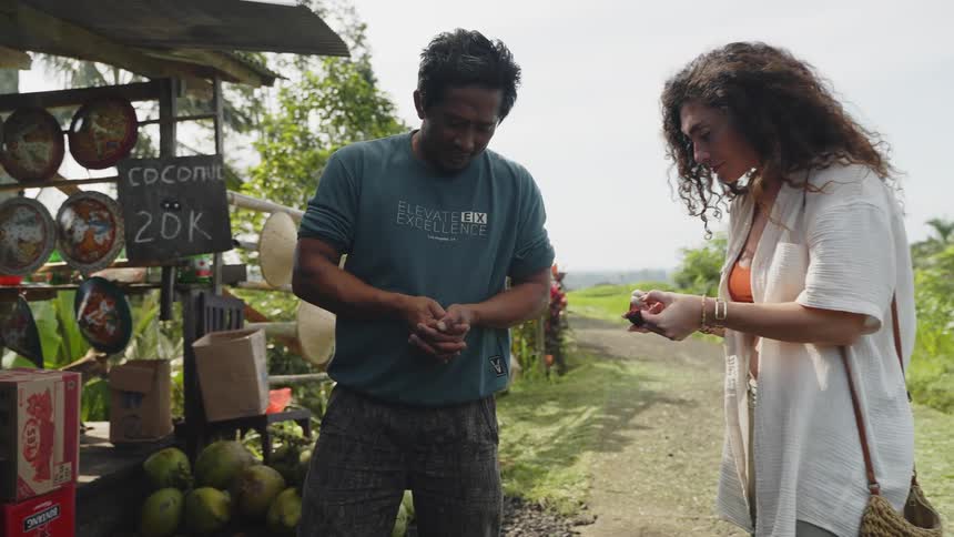 A woman buying local food from a vendor on a roadside stall