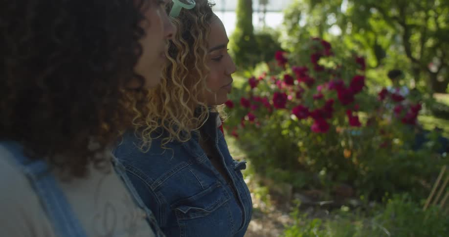 Two women stand side by side looking at a lush green flowering garden