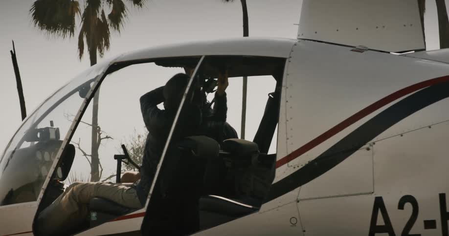 A female pilot and her male copilot sitting in a helicopter sitting out in nature