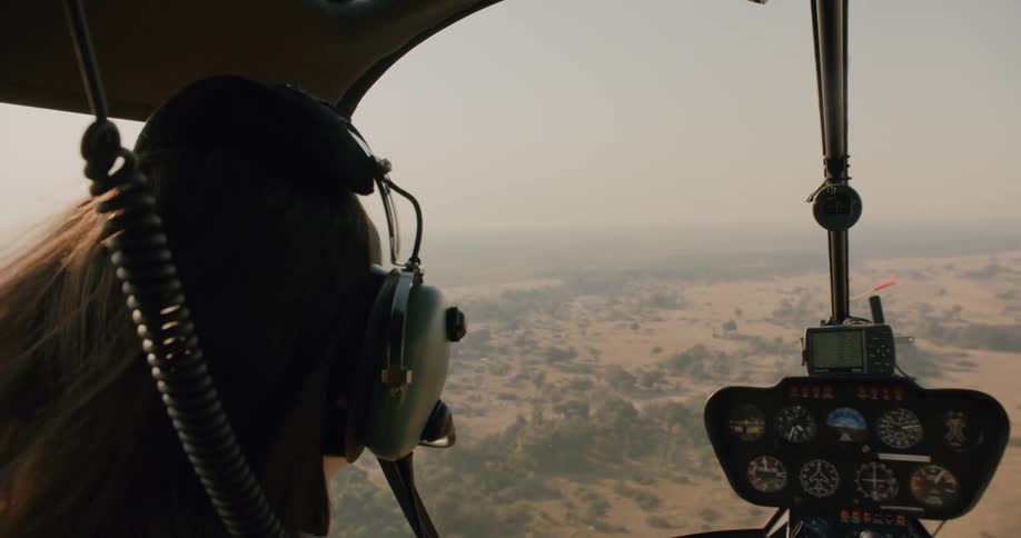 Woman sitting on the front deck of a helicopter flying over a jungle