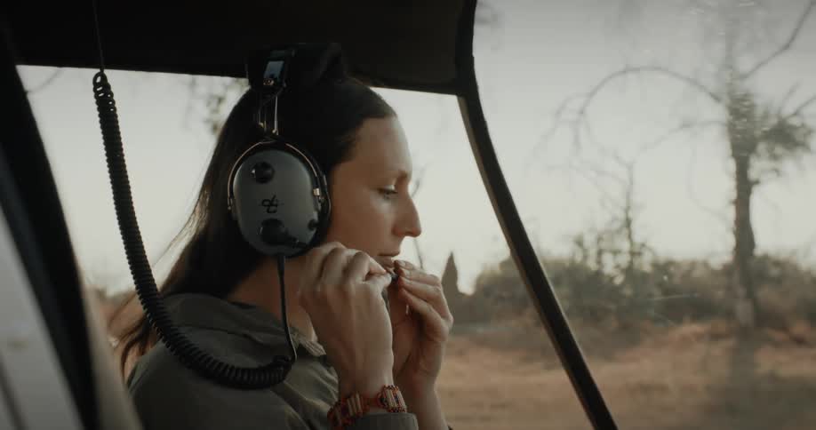 A female helicopter pilot dons her headset
