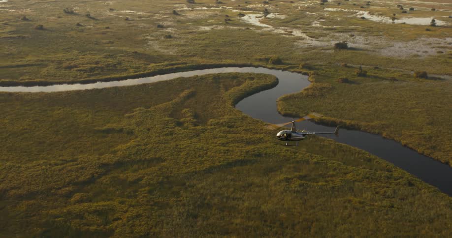 Aerial panorama of a helicopter that is flying above a greenish natural environment and with river