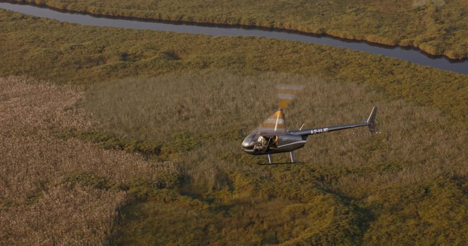 Aerial panorama of a helicopter flying over a greenish area with rivers on the Okavango Delta
