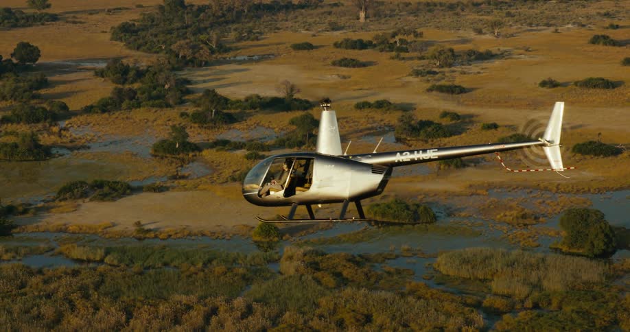 Helicopter flying over a greenish natural area with rivers on the Okavango Delta