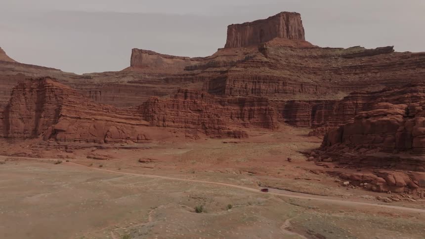 Aerial view of a jeep traveling along a road surrounded by canyons