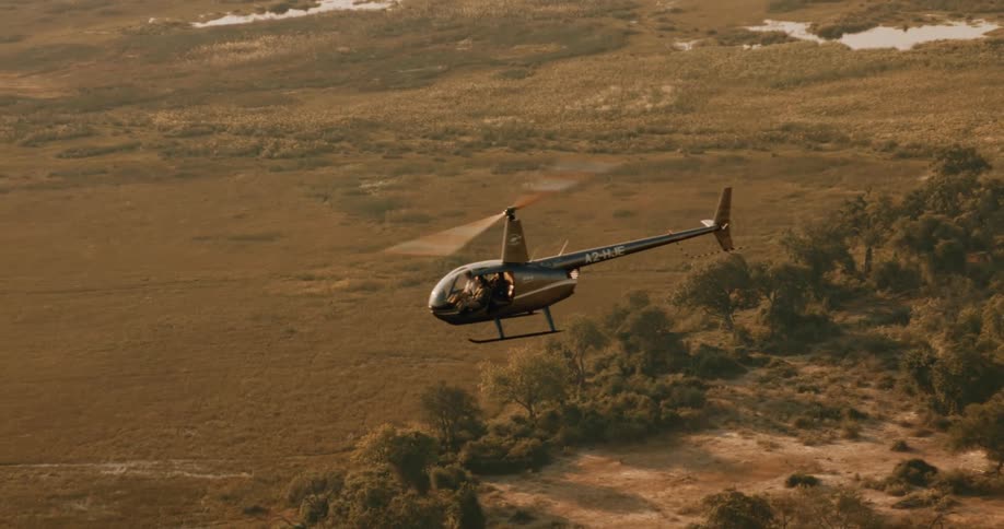 A black helicopter flying over the swamps of the Okavango Delta