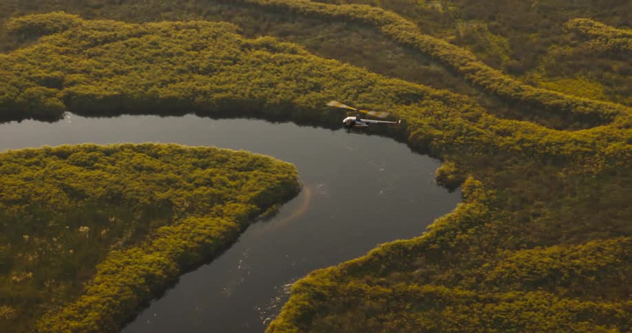 Aerial view of a helicopter flying over a jungle with natural areas and winding rivers