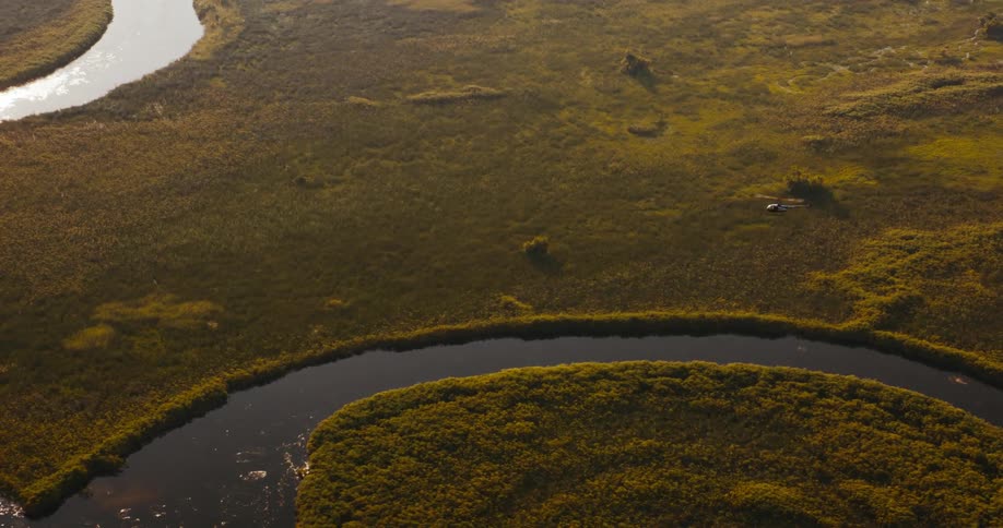 Helicopter flying over a natural environment with a winding river and green areas