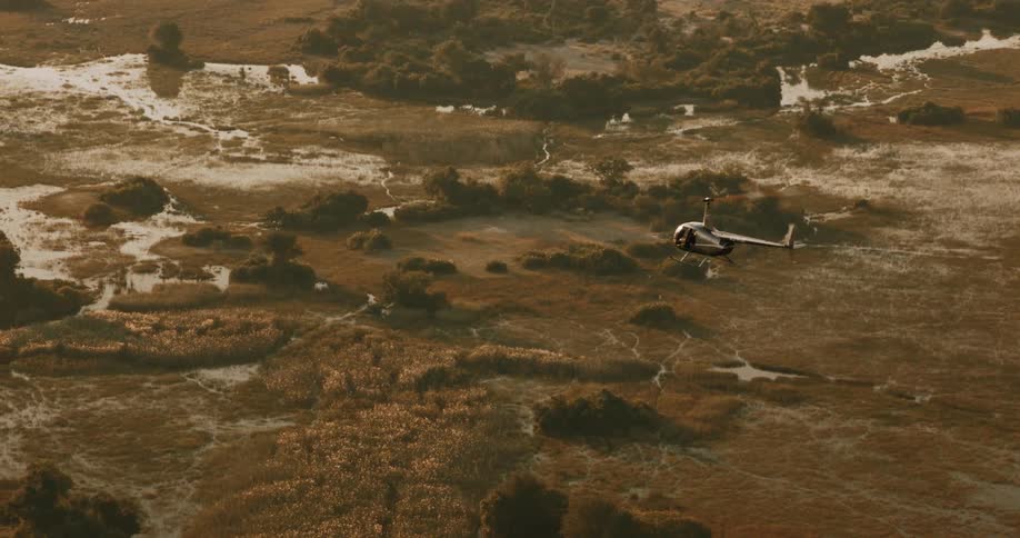 A small helicopter flying over an environment with vegetation and small streams