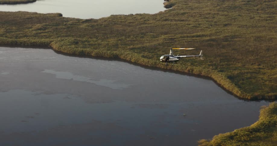 A helicopter flies over the swamp of the Okavango Delta