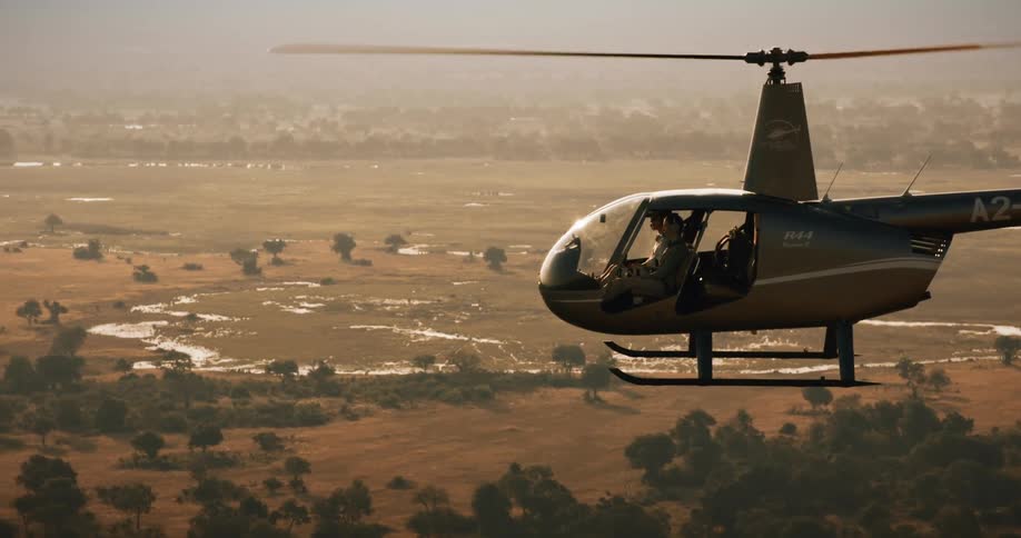 Two crew members in a helicopter flying over the swamps of the Okavango Delta