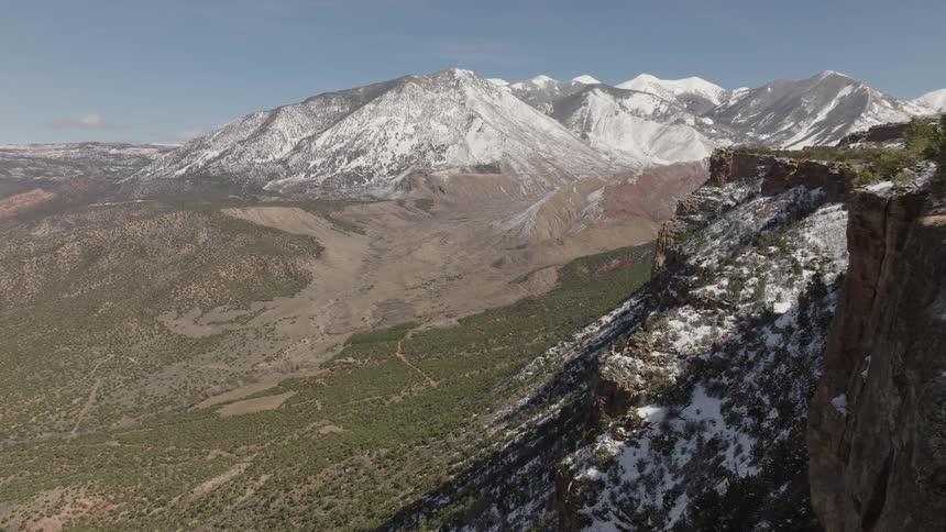 Aerial landscape of cliffs in mountains with snowcapped peaks during a day