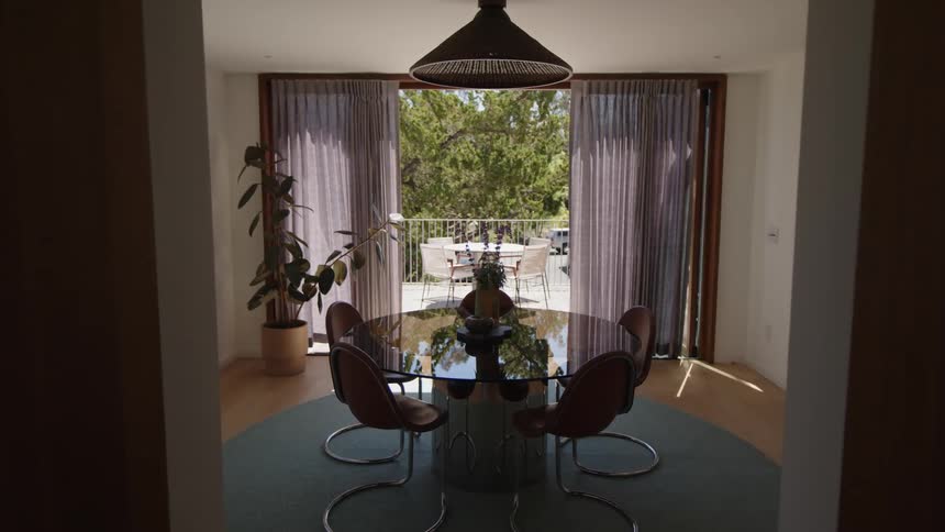 A minimalist dining room a round table with four chairs in the center natural light streams in through the window looking at a patio
