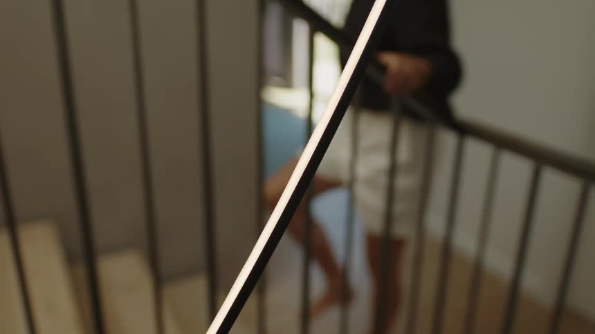A black handrail with an outoffocus human figure ascending a staircase