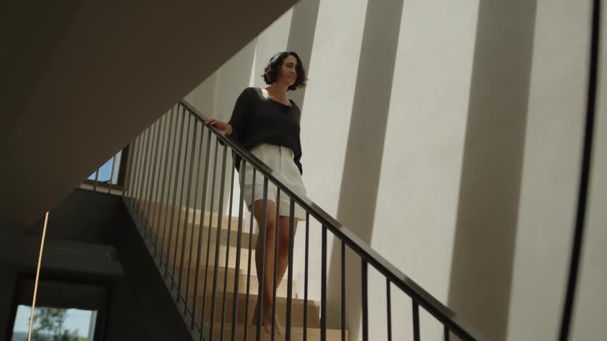 Woman going down the stairs while leaning on the handrail