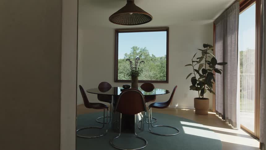 A minimalist dining room a round table with four chairs in the center natural light streams in through the window
