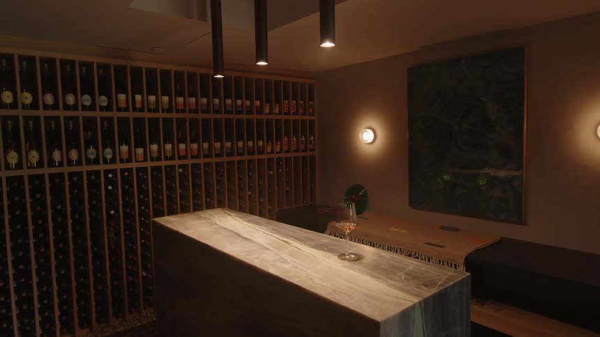 Glass of wine on a wooden bench in a room with a winery in the background