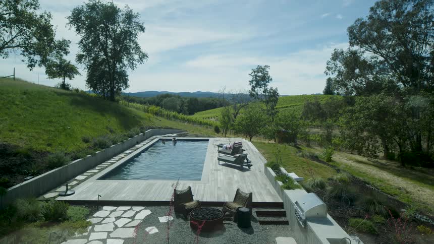 A swimming pool with a wooden deck around it with some outdoor furniture
