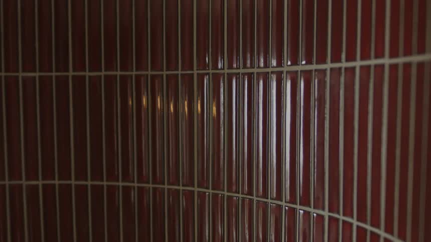 A close up of a wall covered in thin deep red ceramic tiles