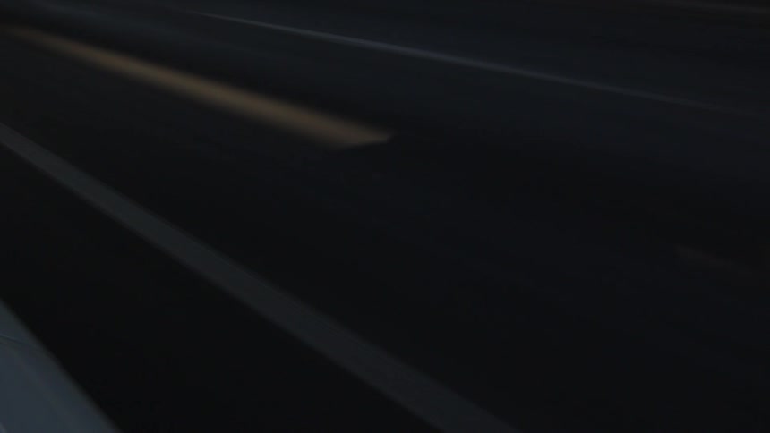 Silhouette of a car traveling along a dark highway
