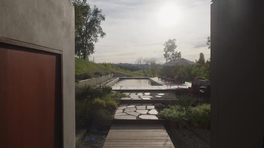 A modern garden pathway leads to a rectangular swimming pool with stepping stones