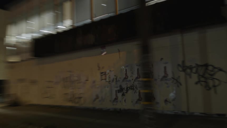 Turn is made at an intersection near a graffiti covered commercial building at night
