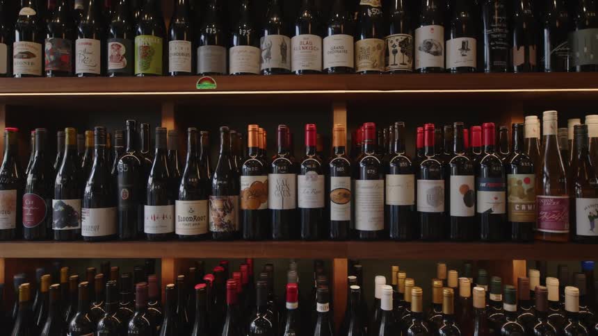 A collection of various wine bottles arranged on wooden shelves with labels facing forward