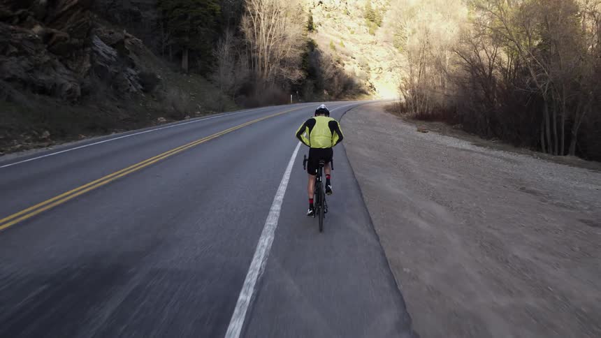 A bicyclist is riding on a mountain road during the day