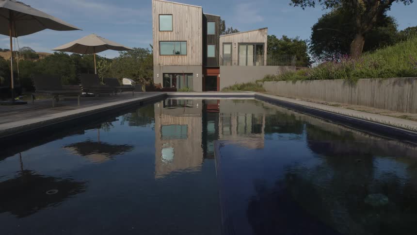 Swimming pool that reflects a modern house in the background