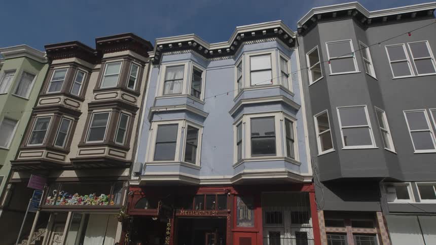 A row of colorful victorianstyle houses with ornate facades against a clear blue sky