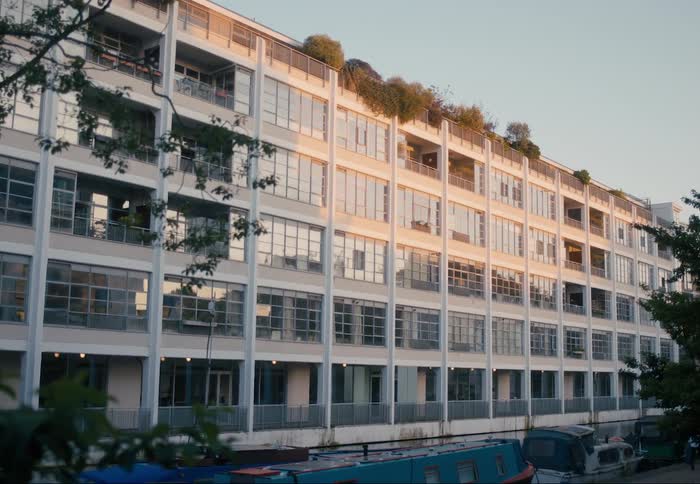 A modern multistory building with balconies adorned by green plants