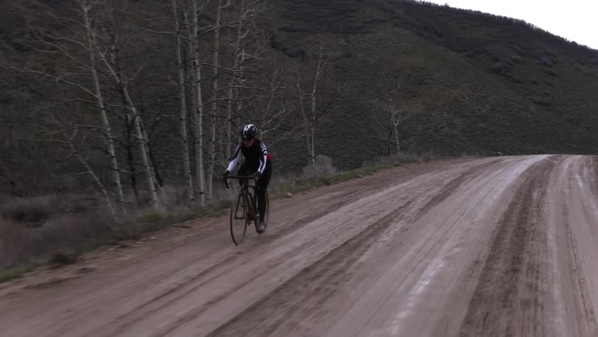 Cyclist pedaling along a wet dirt road