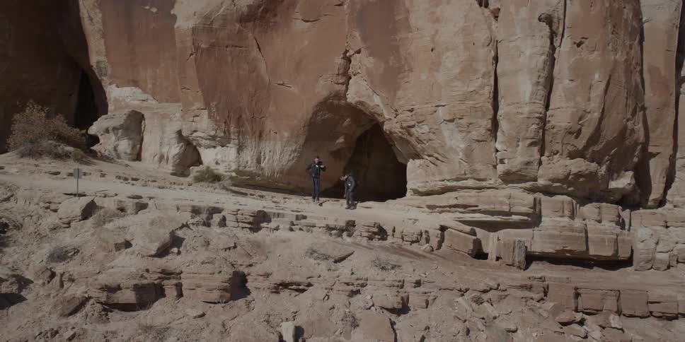 People walk out of a cave mouth and sit down