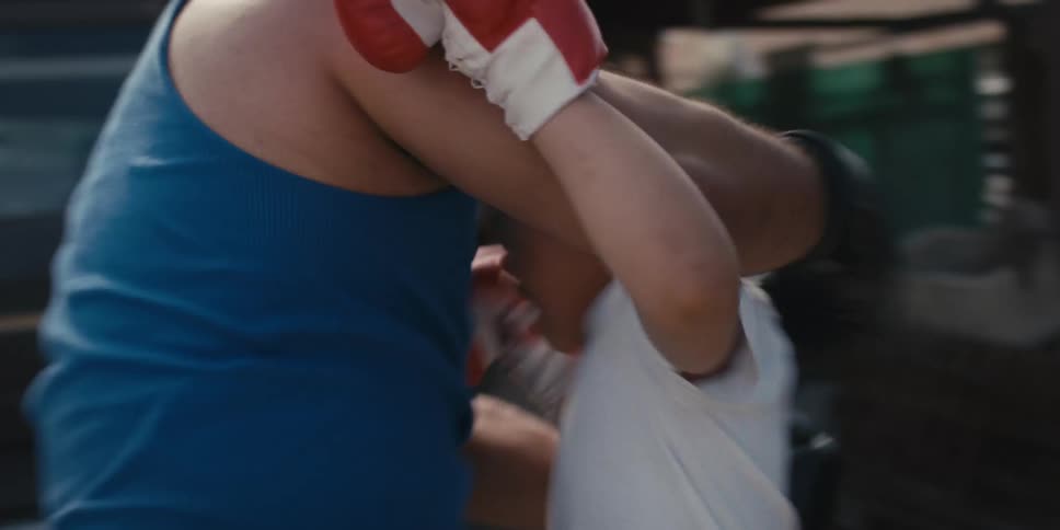 A muscular man wearing a blue undershirt teaching a child how to box in the backyard