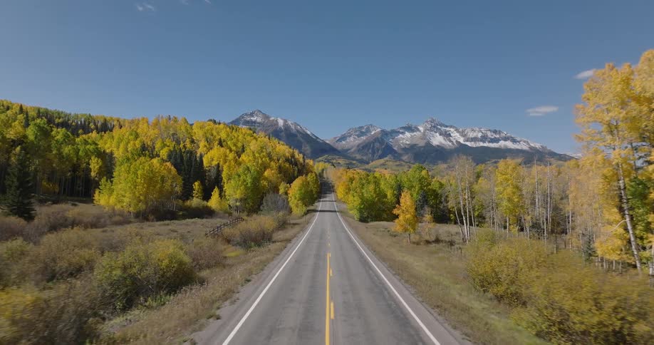 Aerial landscape of an extensive highway with conifers around and mountains on the horizon