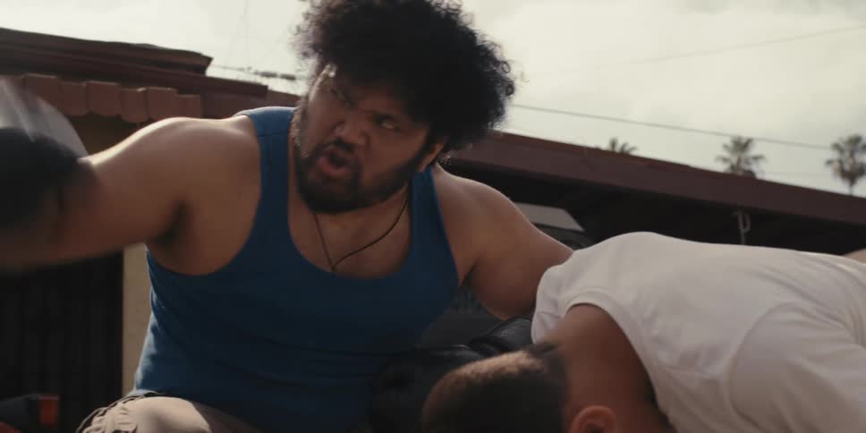 Man with boxing gloves chastises a boy who is kneeling in pain