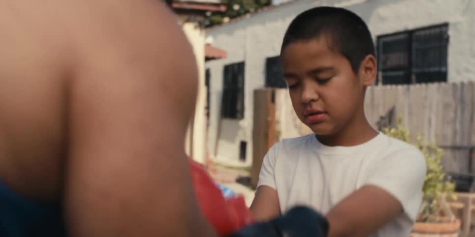 Man roughly handles a boy while both are wearing boxing gloves