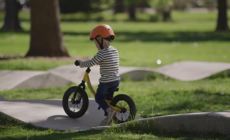 Little blond boy riding a bicycle in a park