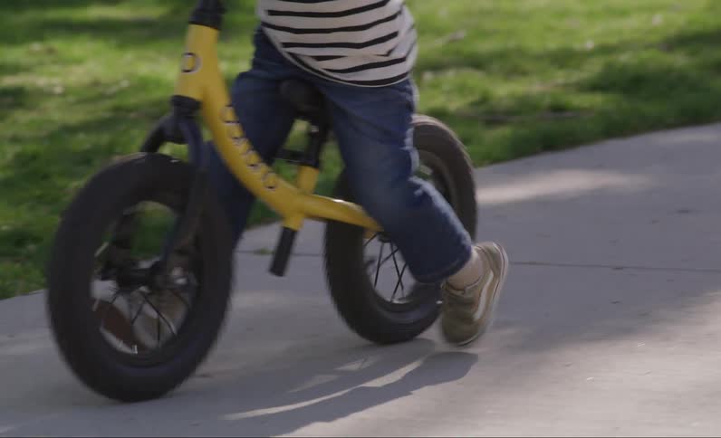 Legs of a child learning to ride a bicycle without support