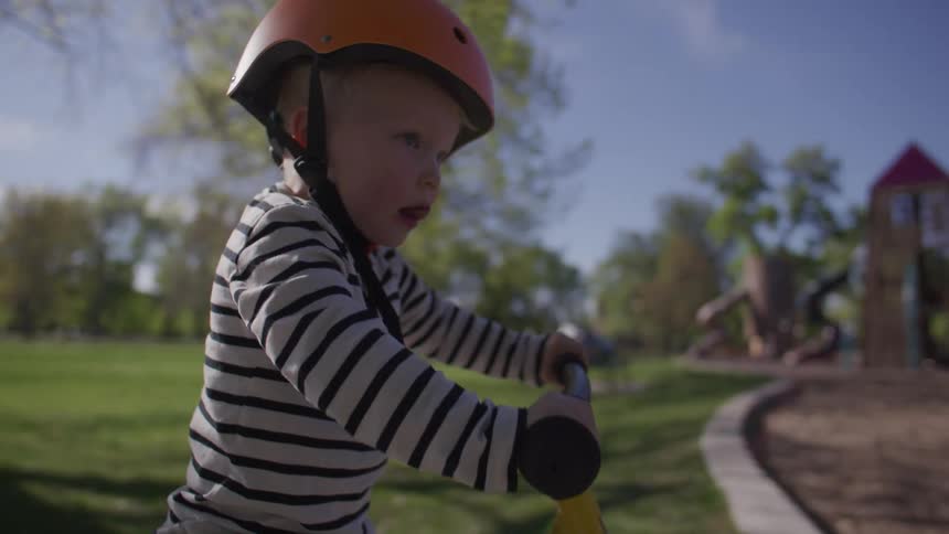 Little blond and small boy riding a bicycle in a park
