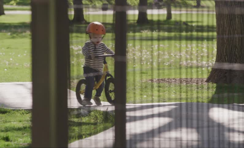 Little boy riding a bicycle on a raised cement track in a park