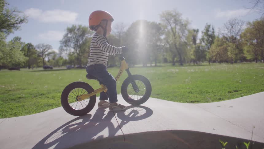 Little boy riding a bicycle with a helmet on a raised track in a park